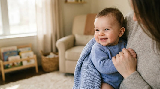 Smiling baby with first tooth showing, held by parent.